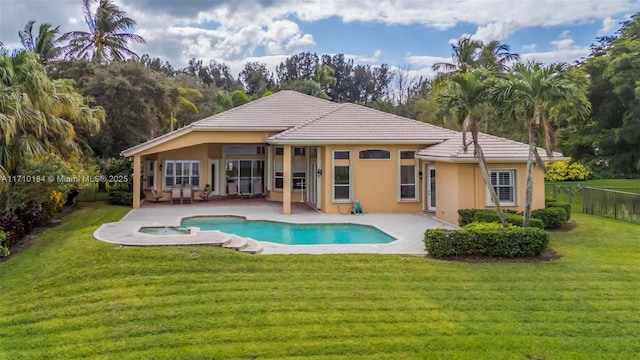 rear view of house featuring a swimming pool with hot tub, a yard, and a patio