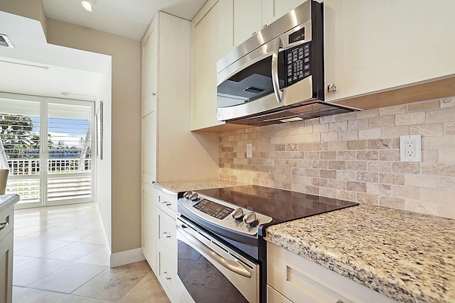 kitchen with white cabinets, backsplash, light stone countertops, and stainless steel appliances