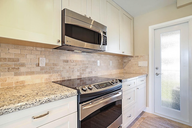 kitchen featuring white cabinets, light stone countertops, stainless steel appliances, and tasteful backsplash