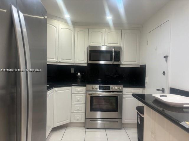 kitchen with decorative backsplash, light tile patterned flooring, white cabinetry, and appliances with stainless steel finishes