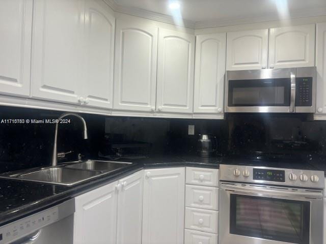 kitchen with tasteful backsplash, white dishwasher, sink, white cabinets, and range