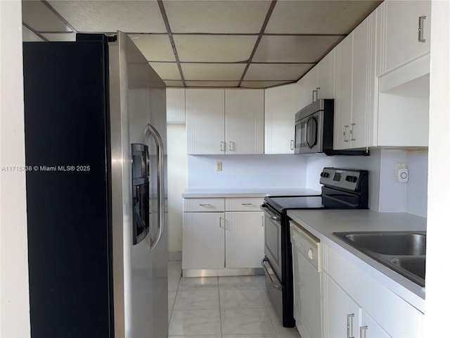 kitchen with a drop ceiling, a sink, light countertops, white cabinets, and appliances with stainless steel finishes