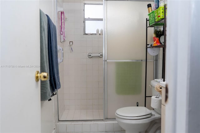 bathroom featuring a shower with door, tile patterned flooring, and toilet