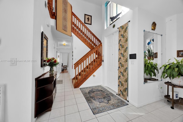 foyer entrance with light tile patterned floors and a towering ceiling