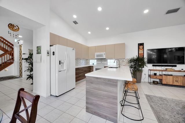 kitchen with decorative backsplash, kitchen peninsula, white appliances, sink, and light tile patterned floors