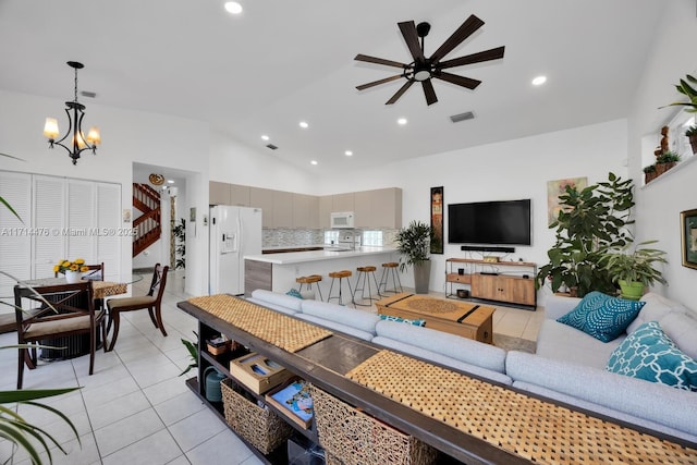 tiled living room featuring ceiling fan with notable chandelier and vaulted ceiling