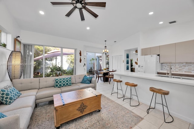 living room featuring light tile patterned flooring, ceiling fan with notable chandelier, vaulted ceiling, and sink