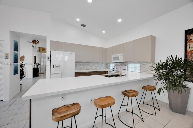 kitchen with sink, kitchen peninsula, white appliances, gray cabinets, and a breakfast bar