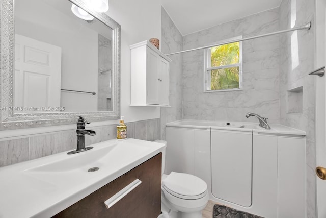 bathroom with vanity, toilet, and a tub to relax in