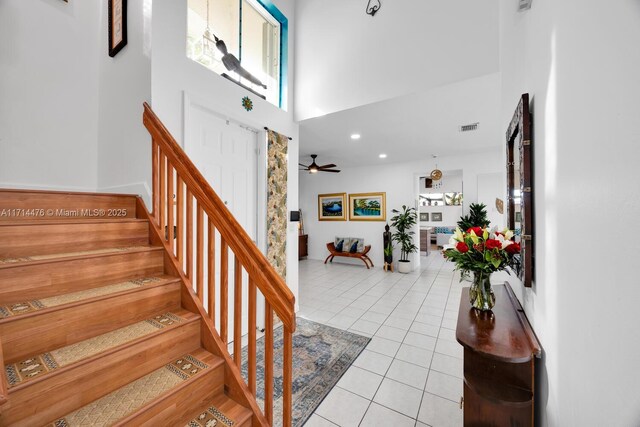 staircase featuring ceiling fan, tile patterned flooring, and a high ceiling