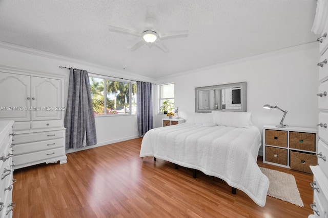 bedroom with ceiling fan, crown molding, light hardwood / wood-style floors, and a textured ceiling