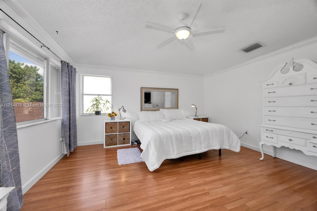 bedroom with a textured ceiling, hardwood / wood-style flooring, ceiling fan, and ornamental molding