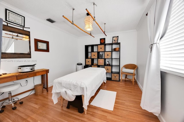 bedroom with light hardwood / wood-style flooring, a textured ceiling, and ornamental molding