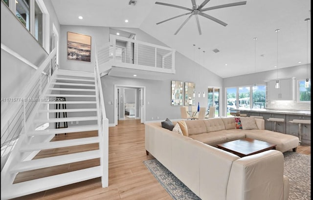 living room featuring ceiling fan, light wood-type flooring, and high vaulted ceiling