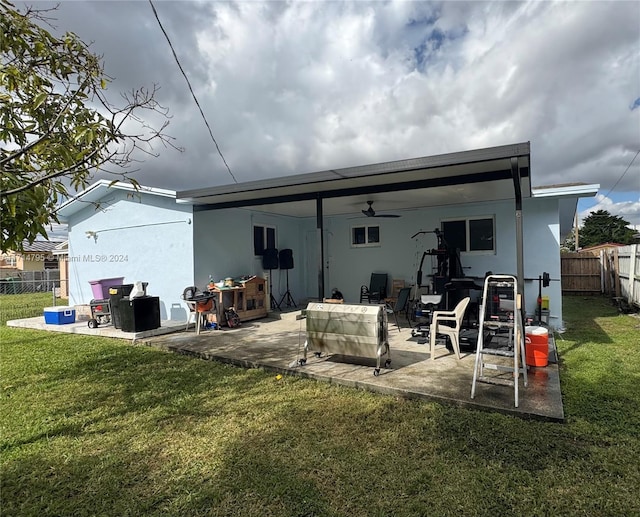 rear view of house with ceiling fan, a patio area, and a lawn