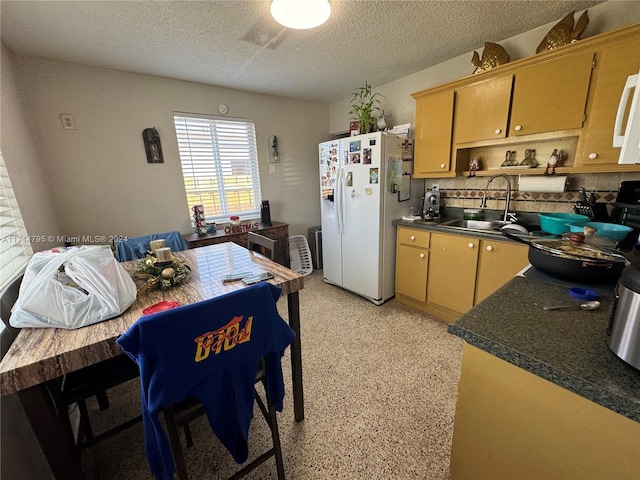 kitchen with a textured ceiling, white fridge with ice dispenser, and sink