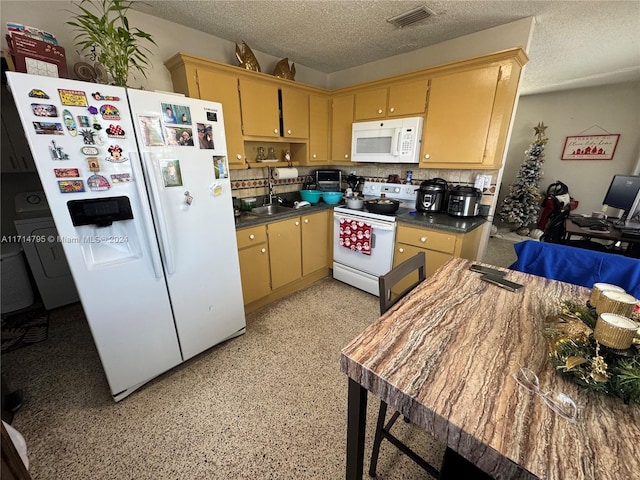 kitchen with a textured ceiling, sink, white appliances, and light brown cabinets