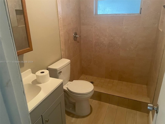 bathroom with vanity, toilet, and a tile shower