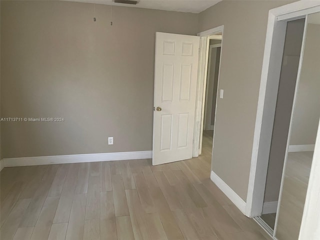 unfurnished bedroom with light wood-type flooring and a closet