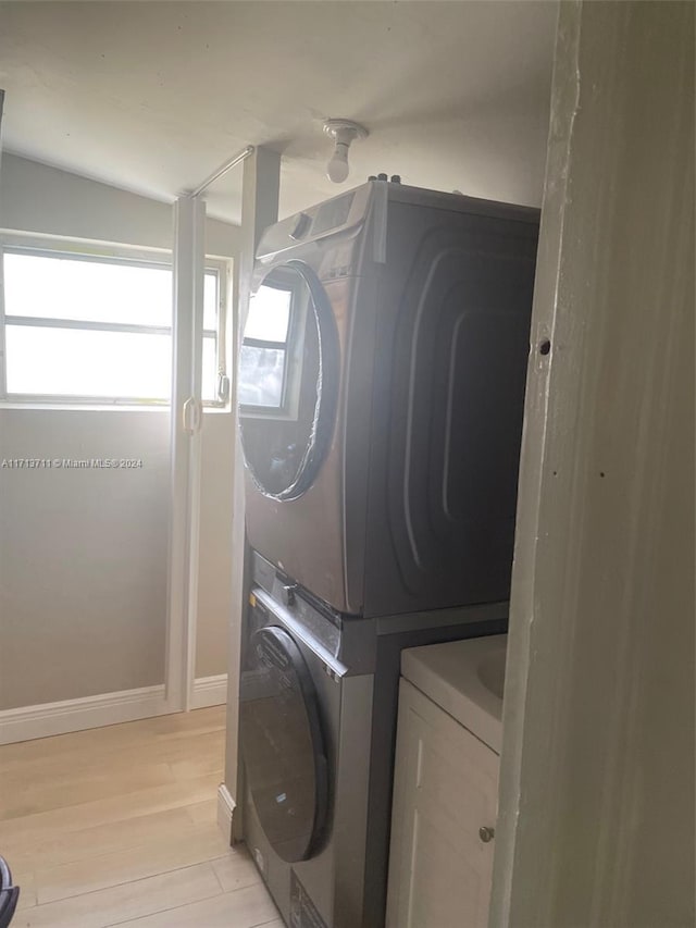 washroom with stacked washer / drying machine and light hardwood / wood-style flooring