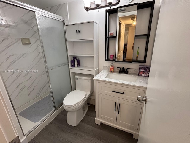 bathroom with hardwood / wood-style flooring, vanity, toilet, and walk in shower