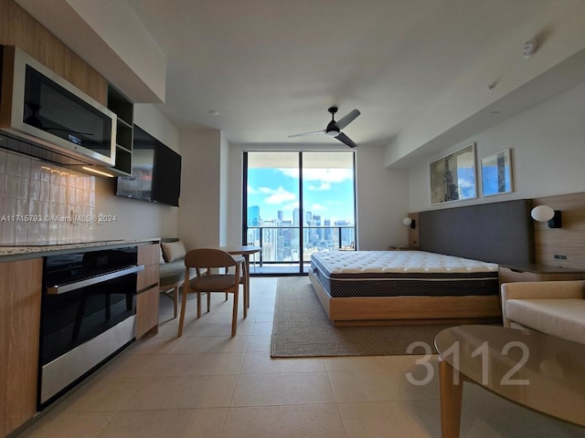 tiled bedroom featuring access to outside, expansive windows, and ceiling fan