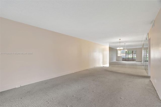 unfurnished room featuring a notable chandelier and light colored carpet