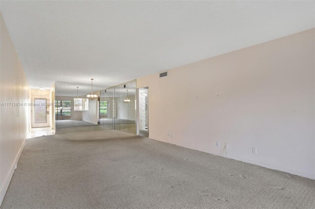 carpeted empty room featuring an inviting chandelier