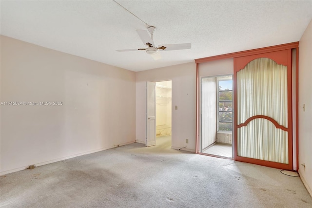 empty room with ceiling fan, light colored carpet, and a textured ceiling