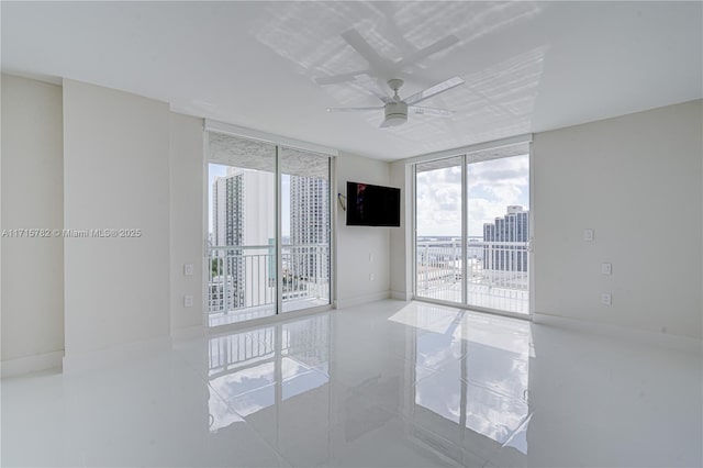 empty room featuring ceiling fan and a wall of windows