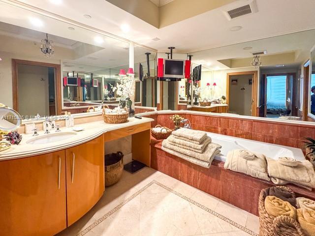 bathroom featuring a raised ceiling, sink, a chandelier, and tile patterned flooring