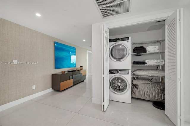 laundry area with stacked washer / dryer and light tile patterned flooring