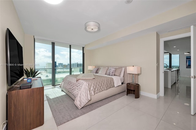 bedroom with sink, access to exterior, and a wall of windows