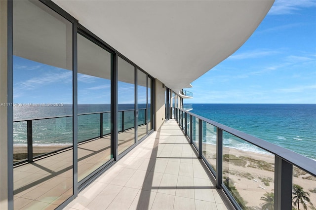 balcony with a water view and a view of the beach