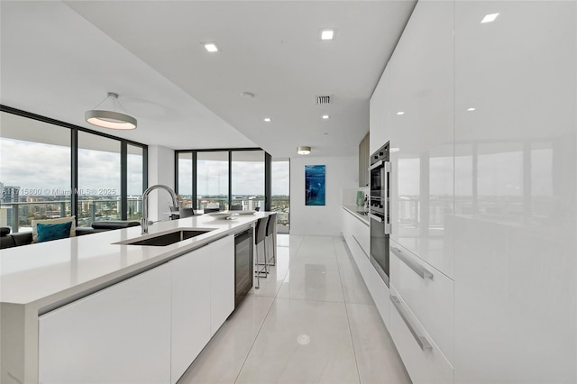 kitchen featuring a large island, sink, expansive windows, and white cabinets