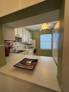 7500 NW 5th Pl Unit 103, Margate, FL 33063 - kitchen featuring white cabinets, white microwave, light countertops, and a ceiling fan