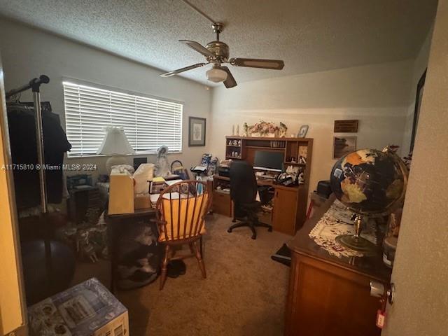 carpeted office with ceiling fan and a textured ceiling