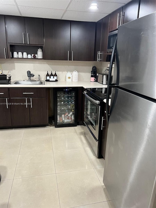 kitchen featuring sink, dark brown cabinets, light tile patterned flooring, stainless steel appliances, and beverage cooler