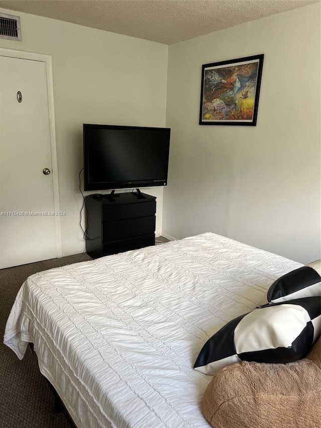 bedroom with carpet floors and a textured ceiling