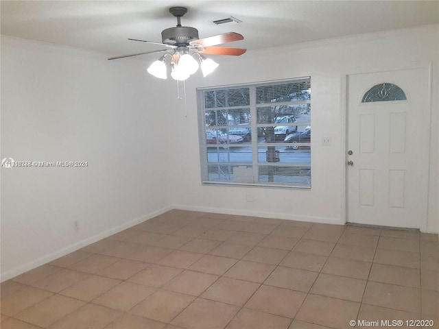 tiled spare room featuring ceiling fan and ornamental molding