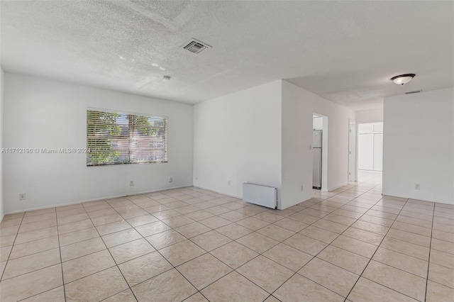 empty room with light tile patterned floors and a textured ceiling