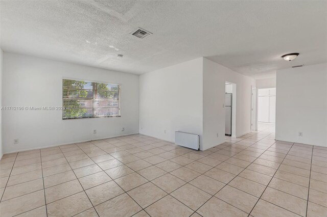 tiled spare room featuring a textured ceiling and plenty of natural light