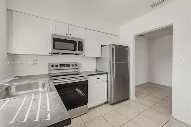 kitchen with light tile patterned flooring, stainless steel appliances, white cabinetry, and sink