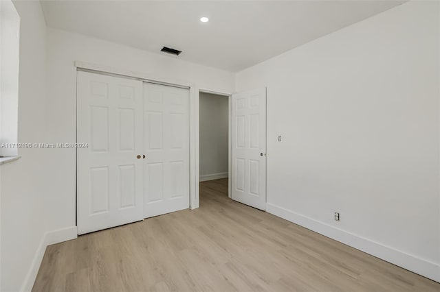 unfurnished bedroom with light wood-type flooring and a closet