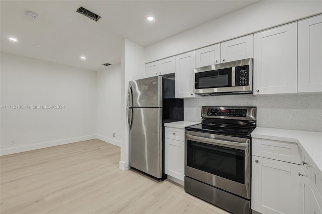 kitchen with white cabinets, light hardwood / wood-style floors, and appliances with stainless steel finishes