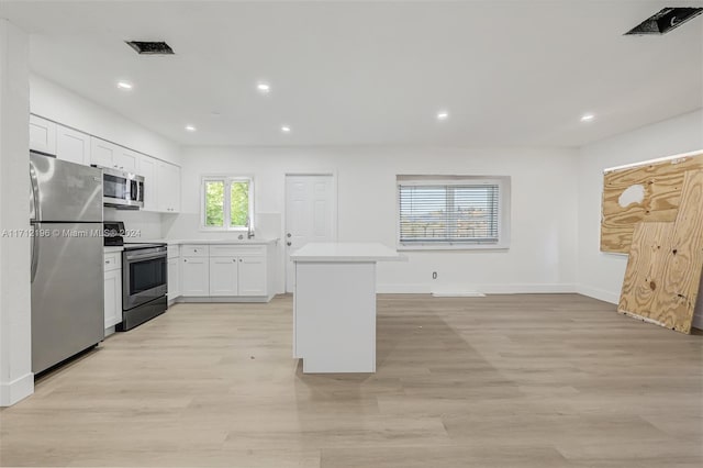 kitchen with white cabinets, light wood-type flooring, and stainless steel appliances