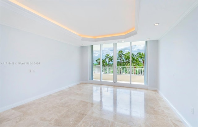 unfurnished room featuring a wall of windows, crown molding, and a tray ceiling