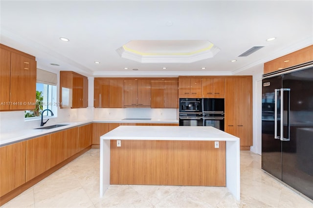 kitchen with a raised ceiling, a center island, ornamental molding, and high end black refrigerator