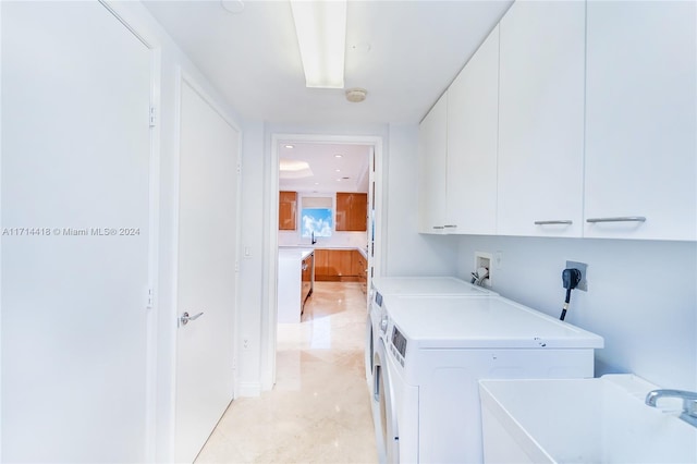 clothes washing area with cabinets, washer and dryer, and sink