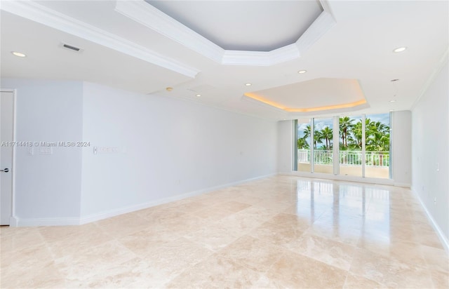 spare room with a tray ceiling, a wall of windows, and crown molding